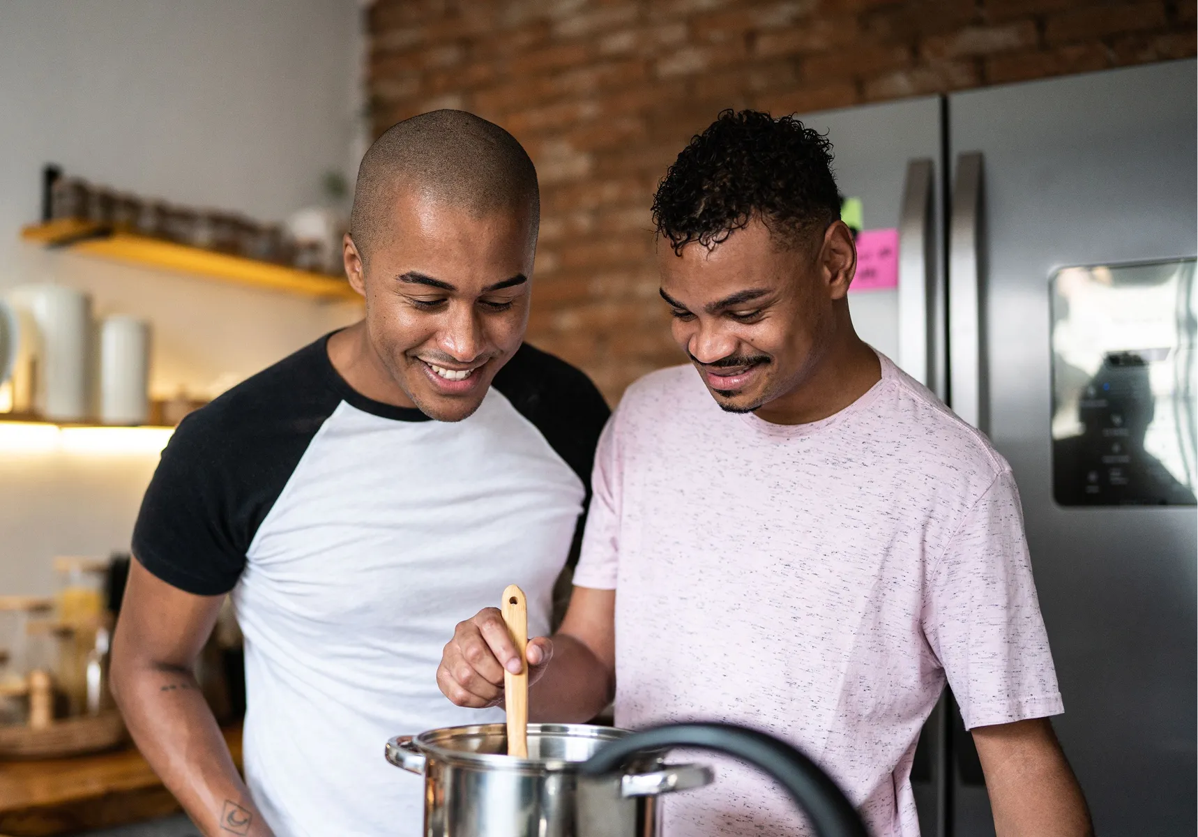 Two young men laughing while cooking together at home